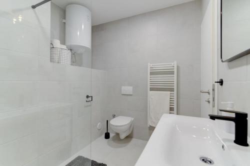a white bathroom with a toilet and a sink at NV Sun 23 by Aneo Travel in Novi Vinodolski