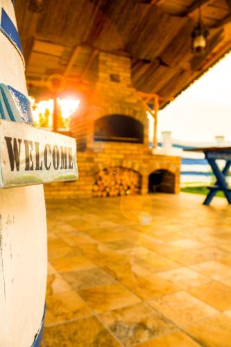 a welcome sign on the side of a house with a fireplace at La Konac in Murighiol