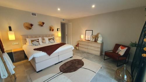 a bedroom with a large white bed and a chair at Pool & Snooker Villa in Finestrat