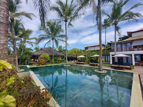 a swimming pool in front of a resort with palm trees at Pousada Vila do Mar in Caraíva