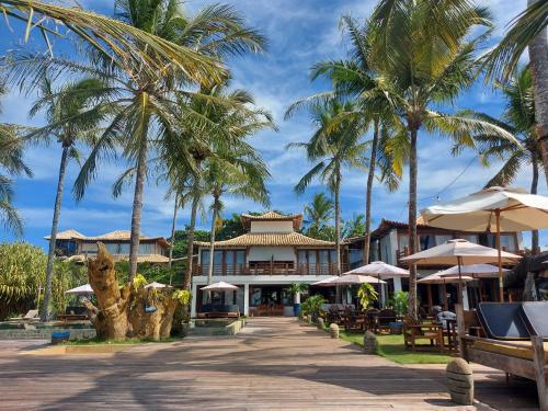 a resort with palm trees and tables and umbrellas at Pousada Vila do Mar in Caraíva