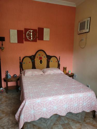 a bedroom with a large bed with an orange wall at Casa aconchegante em Vila Valqueire in Rio de Janeiro