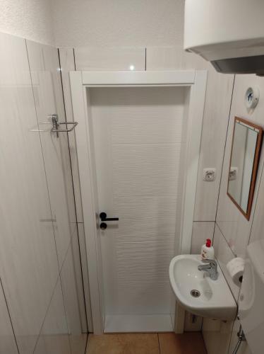 a white bathroom with a shower and a sink at Villa The Cave in Blagaj