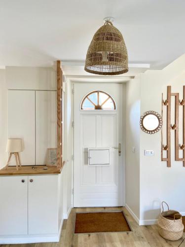 un couloir avec une porte blanche et une lampe pendant dans l'établissement Charmante maison au Port de Sainte Marine, à Combrit