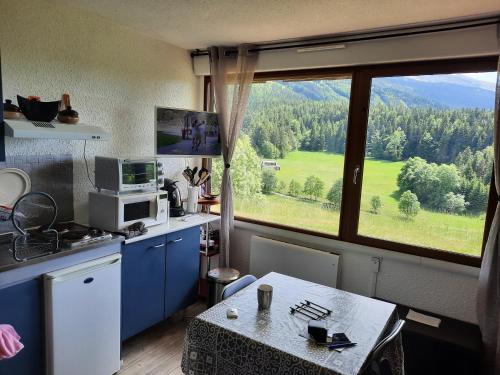 une cuisine avec une table et une grande fenêtre dans l'établissement les glovettes Villard de lans, à Villard-de-Lans