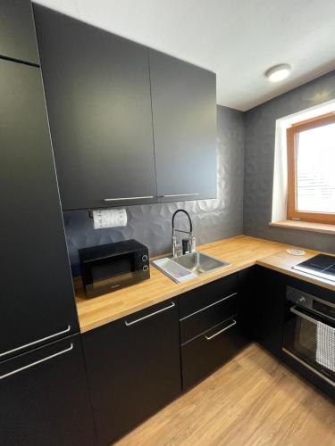 a kitchen with black cabinets and a sink and a window at PineStreet Apartment in Pieve a Nievole
