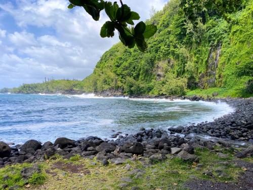 a rocky beach next to the ocean with a mountain at Chalet charmant à Saint-Joseph avec terrasse et jardin in Saint-Joseph