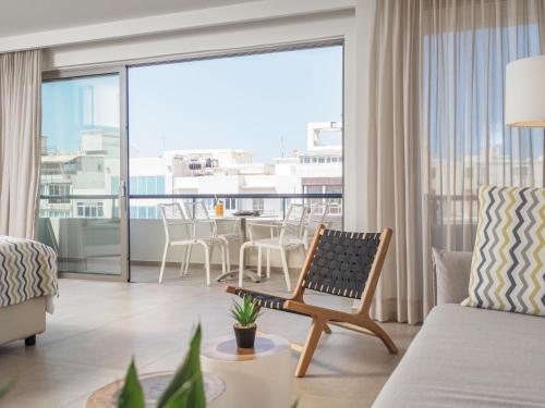 a living room with a couch and a balcony with a table at The H Experience Boutique Apartment Downtown Heraklion in Heraklio