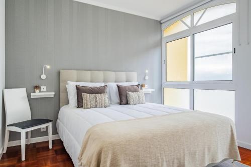 a white bedroom with a large bed and a window at Canico Sea Garden by Madeira Sun Travel in Caniço