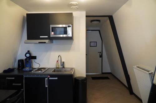 a small kitchen with a sink and a microwave at Haarlem Apart Hotel in Haarlem