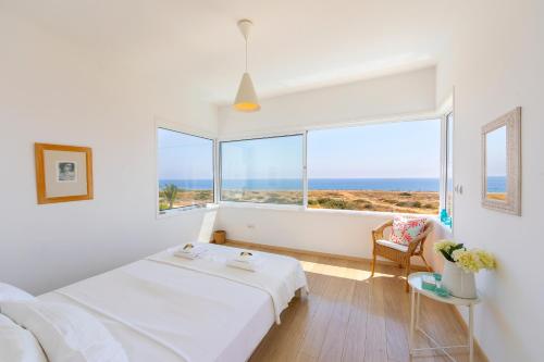 a white room with a bed and a large window at Protaras Beachfront Villa Alia in Protaras