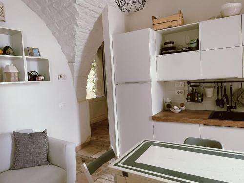 une cuisine avec des placards blancs, une table et une chaise dans l'établissement Casa Nené, à Cisternino