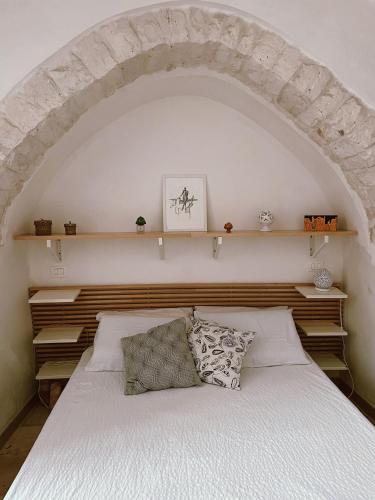 a bedroom with a white bed with shelves above it at Casa Nené in Cisternino