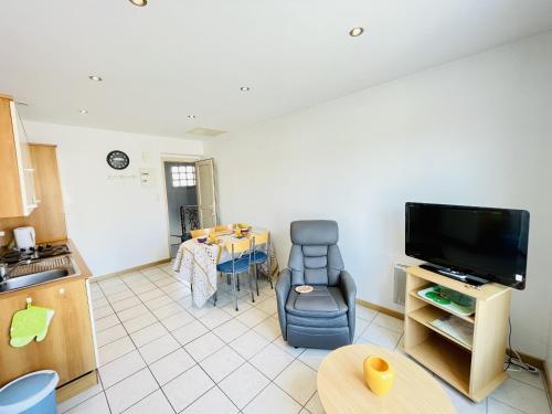 a living room with a kitchen and a tv and a table at Residence Louis Place du Marche in Bains-les-Bains