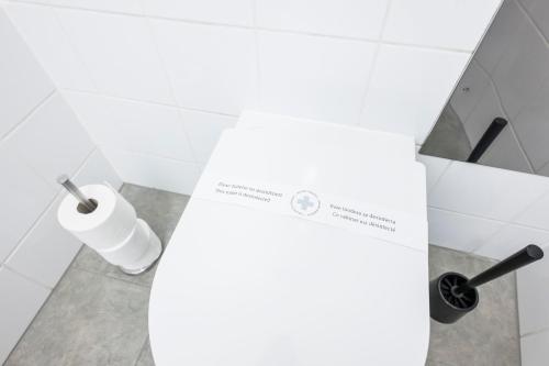 a white bathroom with a roll of toilet paper on a counter at Cozy Kunsthaus GRAZ in Graz