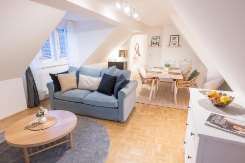 a living room with a blue couch and a table at Cozy Kunsthaus GRAZ in Graz