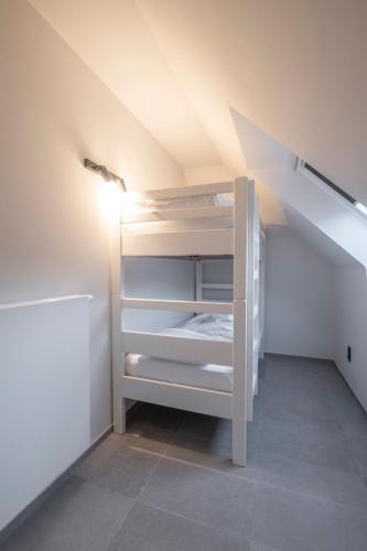 an attic room with a white bunk bed in it at Belcasa Beach Suites & Lofts Aparthotel in Middelkerke