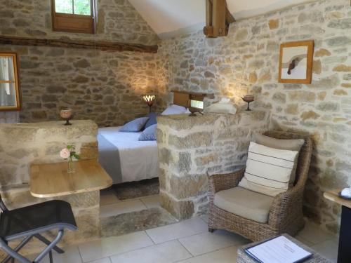 a bedroom with a bed and a chair and a table at Le Hameau du Quercy in Frontenac