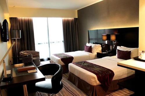 a hotel room with two beds and a desk at Ming Garden Hotel & Residences in Kota Kinabalu