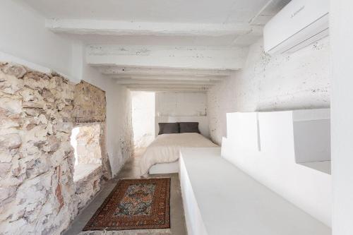 Habitación pequeña con cama y pared de piedra. en La Casa Baja, en Sagunto