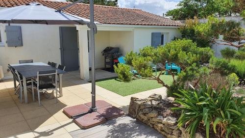 a patio with a table and an umbrella at Villa d'Arçay - ADRIAE Home in LʼAiguillon-sur-Mer