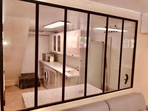 een groot glazen raam in een keuken met een wastafel bij Appartement 120m2 dans maison avec piscine in Boissy-lʼAillerie