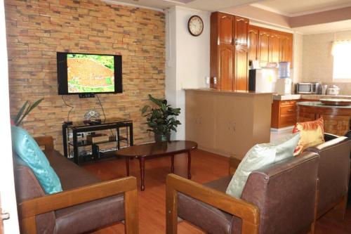 sala de estar con sofá, mesa y TV en Comfy Dwelling en Baguio