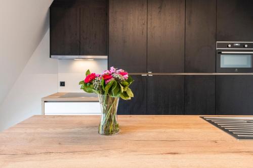 a vase of flowers sitting on a table in a kitchen at Belcasa Beach Suites & Lofts Aparthotel in Middelkerke