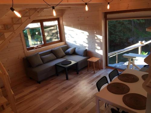 Sala de estar de una cabaña de madera con sofá y mesas en Chatka z sauną nad rzeką en Żabnica