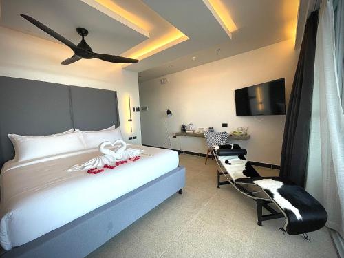 a bedroom with a white bed and a chair at Epic Suites Bohol ADULTS ONLY in Dauis