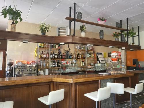 a bar with white chairs in a restaurant at Alberg Restaurant Bellavista in Santa Pau