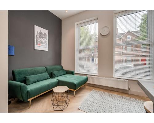a living room with a green couch and two windows at Central Belfast Apartments: University Street in Belfast