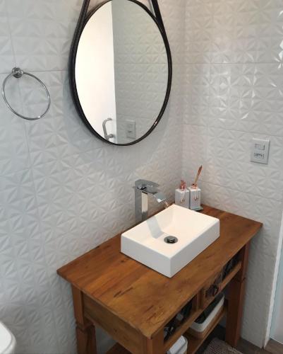 a bathroom with a white sink and a mirror at Apartamento Duda 03 in Monte Verde