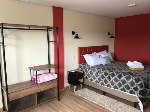 a bedroom with a bed and a red wall at Apartamento Duda 03 in Monte Verde