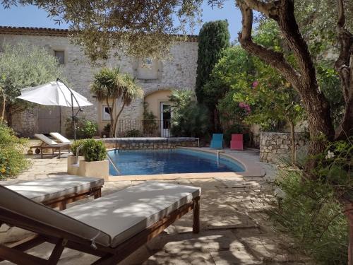 una piscina en un patio con una casa en La Maison Des Autres, piscine chauffée, chambres d'hôtes proches Uzès, Nîmes, Pont du Gard en Saint-Géniès-de-Malgoirès