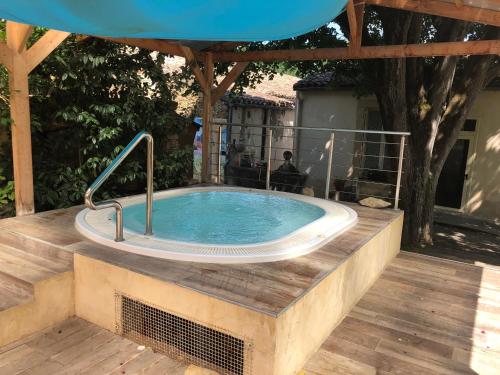 a jacuzzi tub on a deck with an umbrella at La Vie en Roses in Rennes-les-Bains