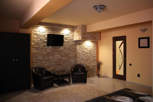 a living room with two chairs and a stone wall at Apartament Modern in Craiova