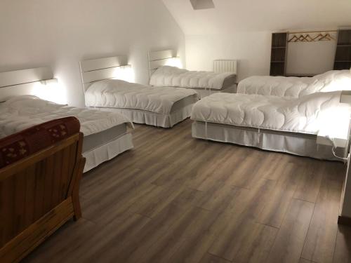 Habitación con 4 camas y suelo de madera. en MAISON MEDIEVALE, en Sarrancolin