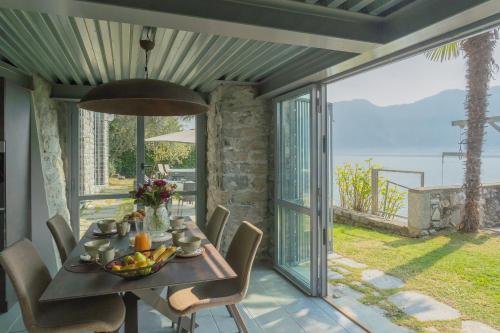 a dining room with a table and a view of the ocean at Villa Sasso On Lake Como by Rent All Como in Sala Comacina