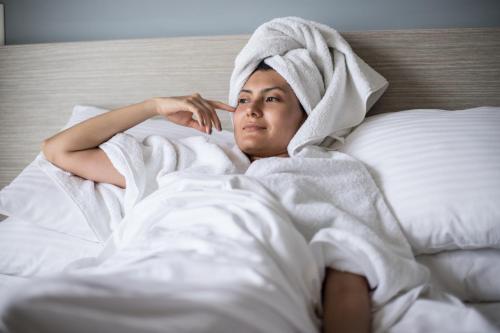 a woman laying in bed with a towel on her head at Hotel Rilux Tolu in Tolú