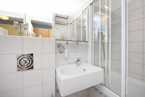 a white bathroom with a sink and a shower at Hotel Grosuplje in Grosuplje