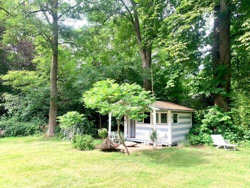 a small white shed in a yard with a bench at la Tour d'Héloïse - 10' de Bruxelles in La Hulpe
