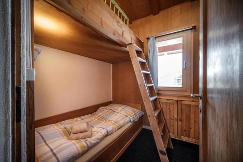 um beliche num pequeno quarto com uma escada em Chalet Höckli Wohnung 1. em Arosa