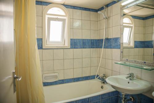 a bathroom with a sink and a tub and a mirror at Cornelia Hotel in Ayia Napa