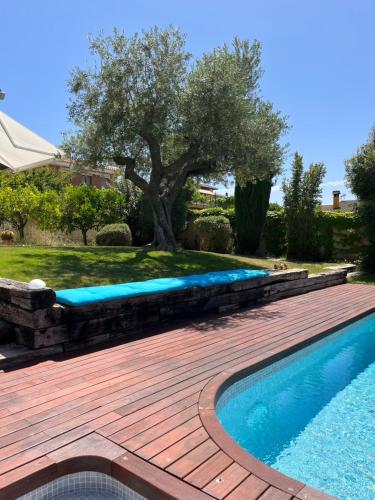 a swimming pool with a wooden deck next to a tree at Les Columnes in Vespella de Gaià 