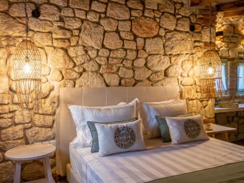 1 dormitorio con cama y pared de piedra en Petrino Eco Village en Áfitos