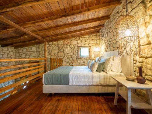 1 dormitorio con cama y pared de piedra en Petrino Eco Village, en Afitos