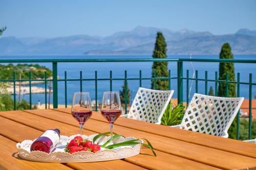 einen Holztisch mit zwei Gläsern Wein und Erdbeeren in der Unterkunft Villa Spiros Imerolia Kassiopi in Kassiopi