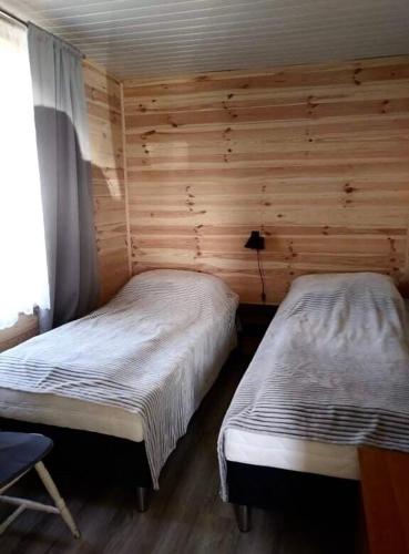 2 camas en una habitación con paredes de madera en Domek DaNutka w Sarbinowie, en Sarbinowo