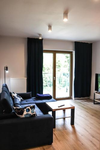 a living room with a black couch and a table at Lemon Park Apartments Parking Gratis in Poznań
